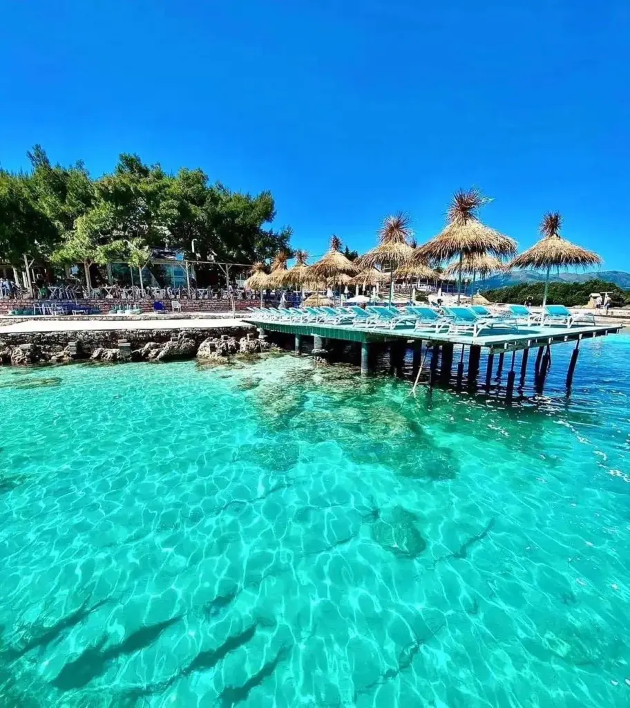 Ksamil beach with clear blue waters and nearby islands, ideal for travelers using Ksamil car rental services to explore Southern Albania.