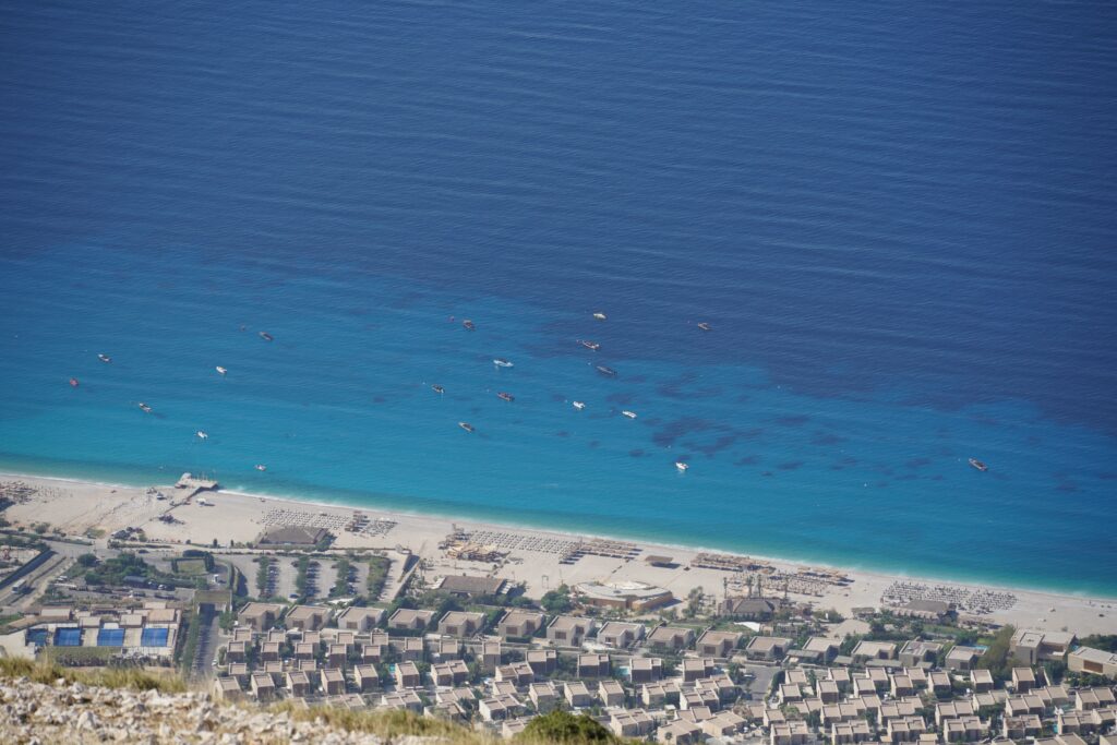 Aerial view of a beach resort and boats floating in the Ionian Sea, Albanian Riviera coast