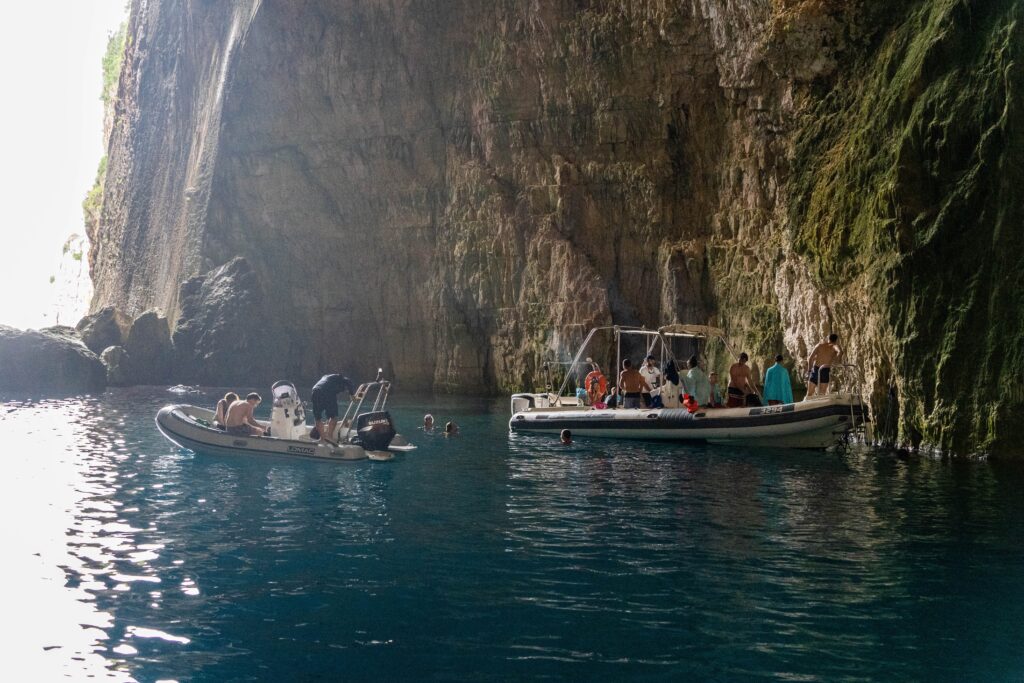 Tourists swimming and relaxing on boats inside the Haxhi Ali Cave during a Vlora boat trip in Albania.