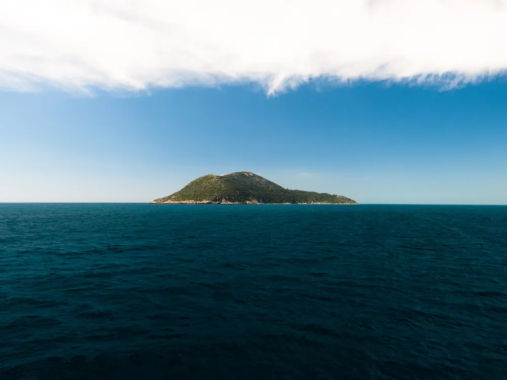 View of Sazan Island from the sea on a sunny day, a historical highlight of the Vlora boat trip in Albania.

