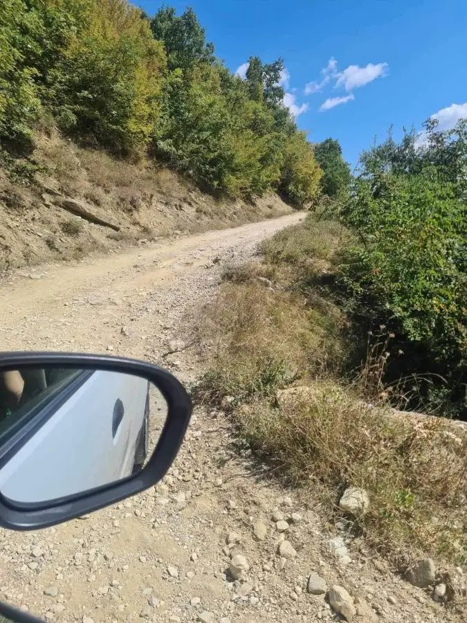 Rough gravel mountain road to Theth, Albania, seen from a rental car — a high-risk area for tire, undercarriage, and windshield damage not covered by basic CDW insurance.
