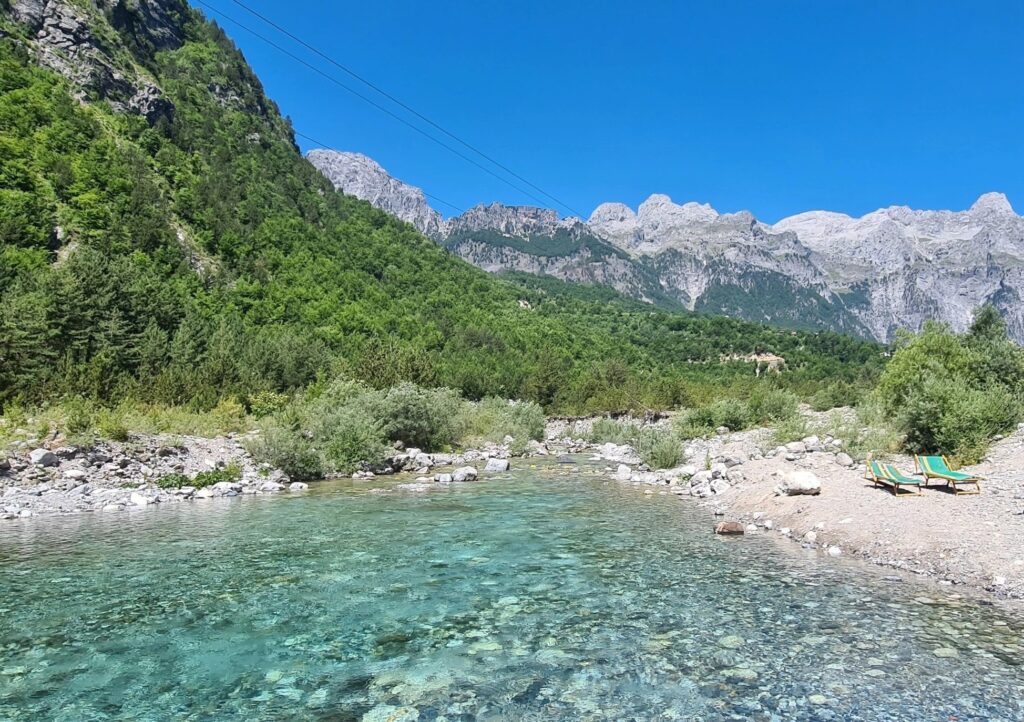 Best car for the Albanian Alps – crystal clear water at Theth Blue Eye spring with mountains in the background