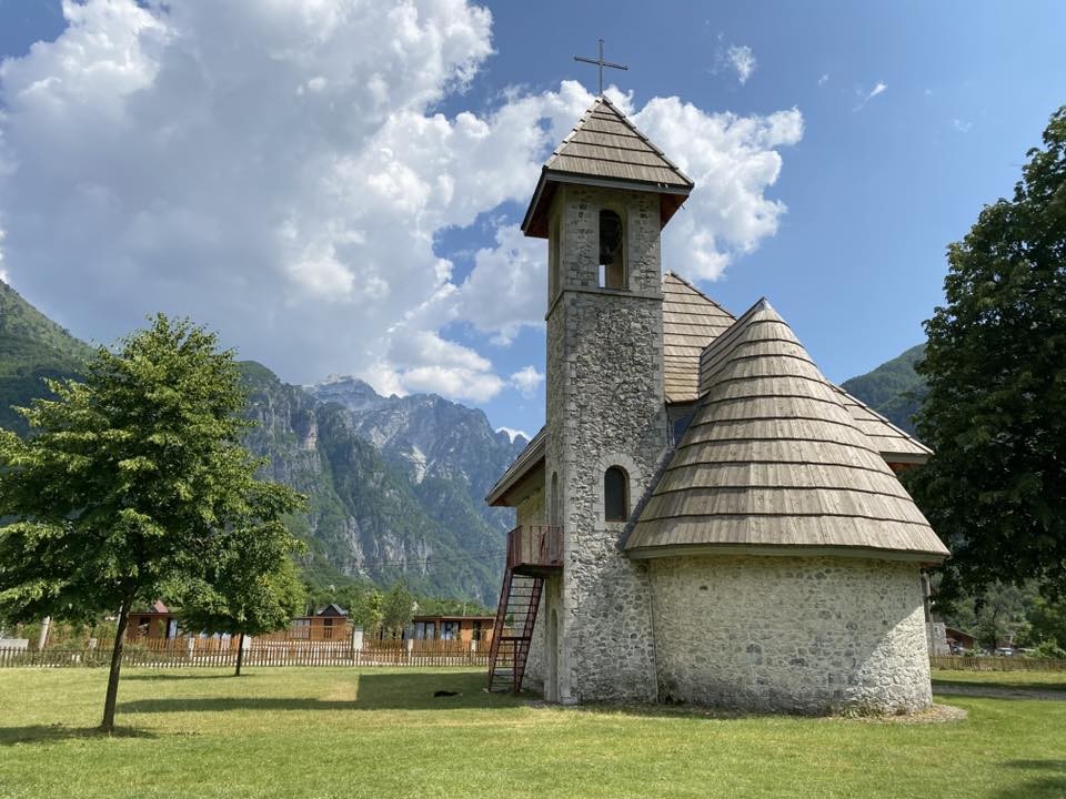 Best car for the Albanian Alps – historic stone church in Theth village with mountains in the background