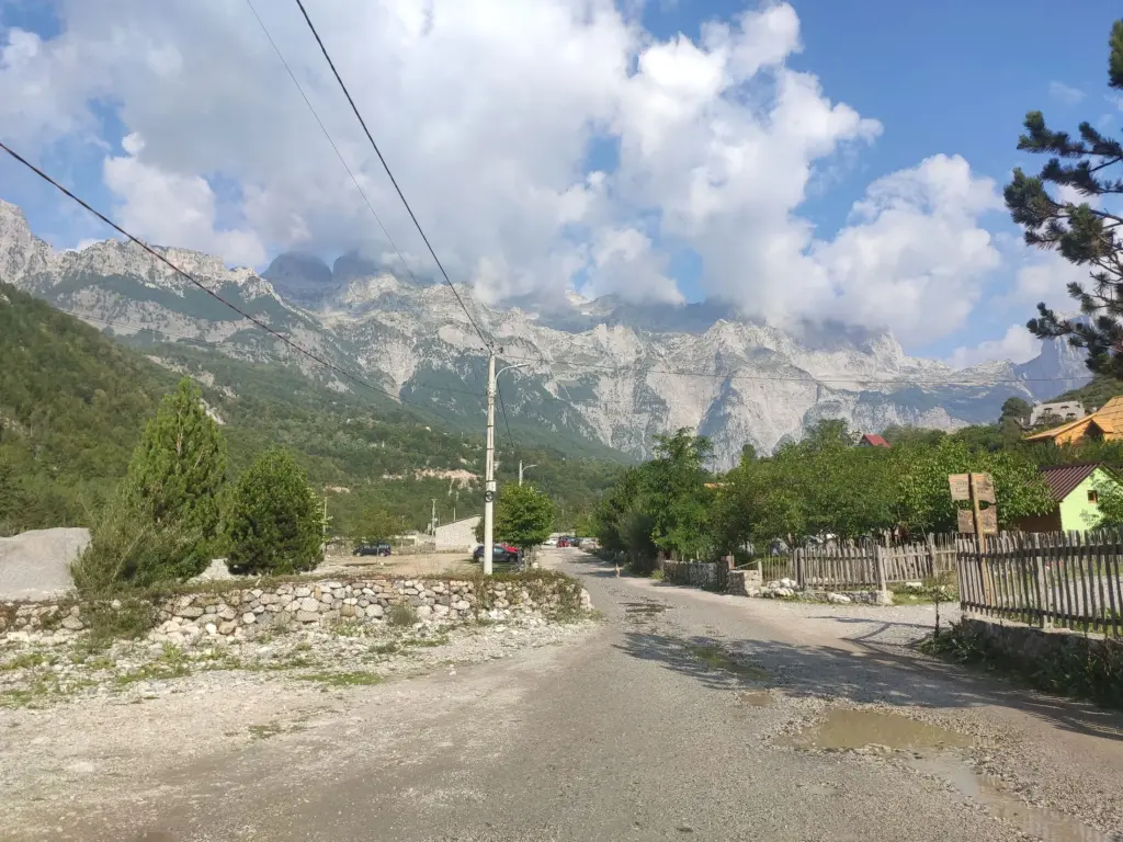 Gravel road with potholes in Theth village, showing that while the SH21 road is paved to the village, local streets may require careful driving and the right vehicle choice.