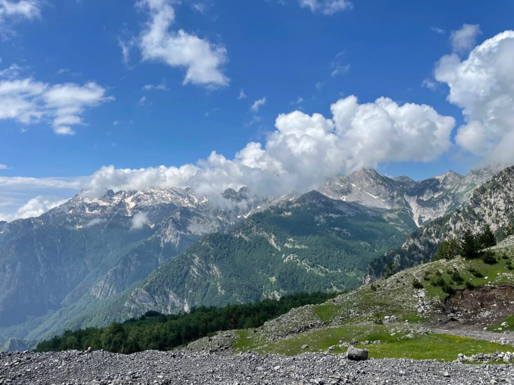 Panoramic view of the Albanian Alps from Thore Pass on the SH21 road to Theth, with rocky slopes and lush green valleys.